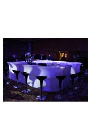 an illuminated bar table with replica bombo stools in the background