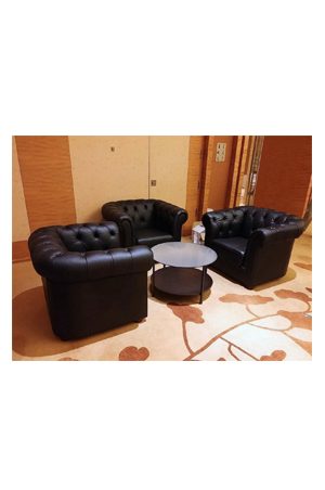 four black leather chairs in a room with a calico round coffee table