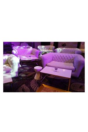 a room with white couches and purple lighting featuring the trays coffee table
