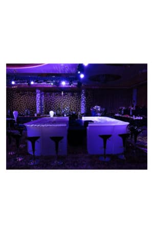 a room with purple lights and an illuminated corner bar set up