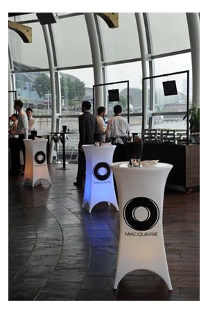 a group of people are standing around an illuminated baron bistro table