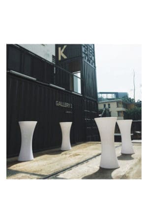 three illuminated hourglass bistro tables in front of a building