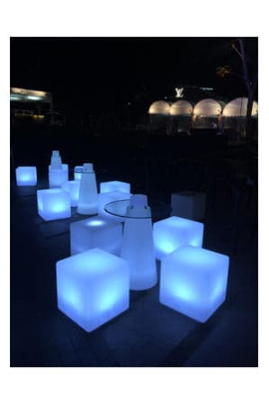 a group of illuminated pinnacle tables on a sidewalk