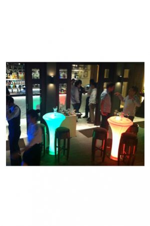 a group of people standing around an illuminated bistro table with lighted tables