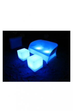 an illuminated baron double seater couch and two blue cubes on the sand