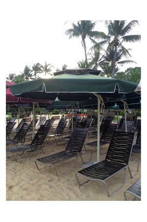 a group of lounge chairs on the beach with parasols