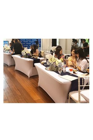a group of people sitting at 6ft long spandex tables at an event